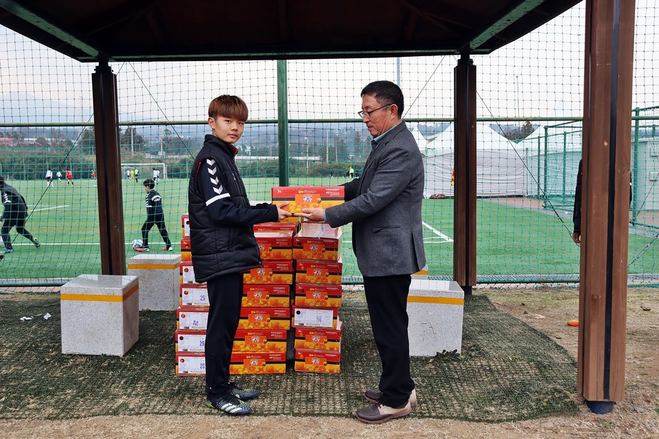 위미농협 오영종 이사가 광명유소년FC축구단에게 감귤을 전달하는 장면이다.(사진=장태욱 기자)