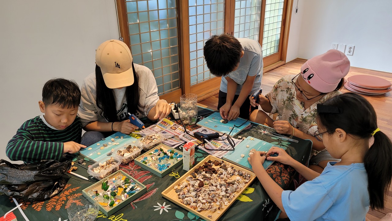 아이들과 학부모들이 수집한 조개껍데기로 가족액자를 만들고 있다. (사진=몽생이다함께돌봄센터)