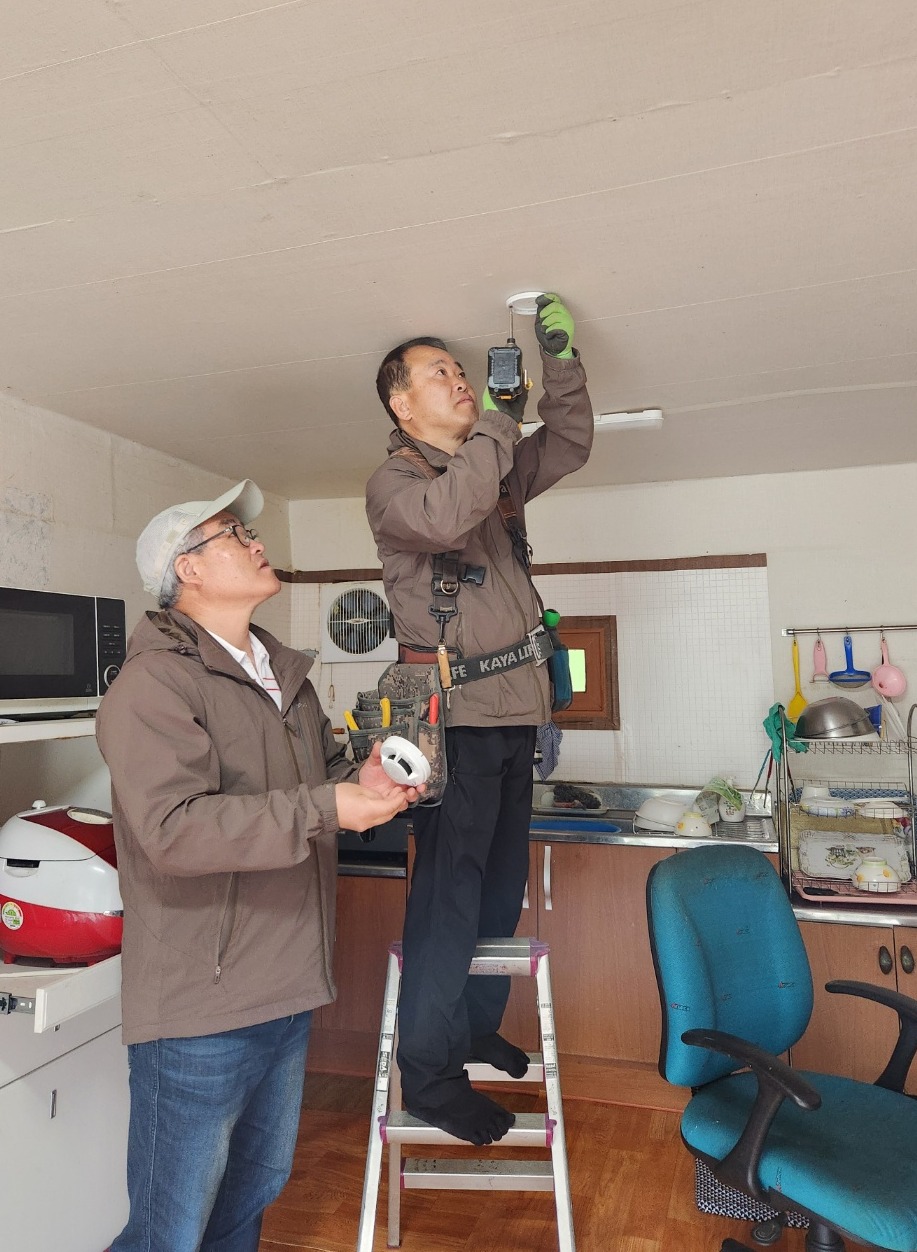 지난 26일 서귀포시 남원읍 한 주택에서 김영효 서귀포시시민안전봉사자협의회장(사진 왼쪽)이 화재경보기 설치 과정을 꼼꼼히 살펴 보고 있다.