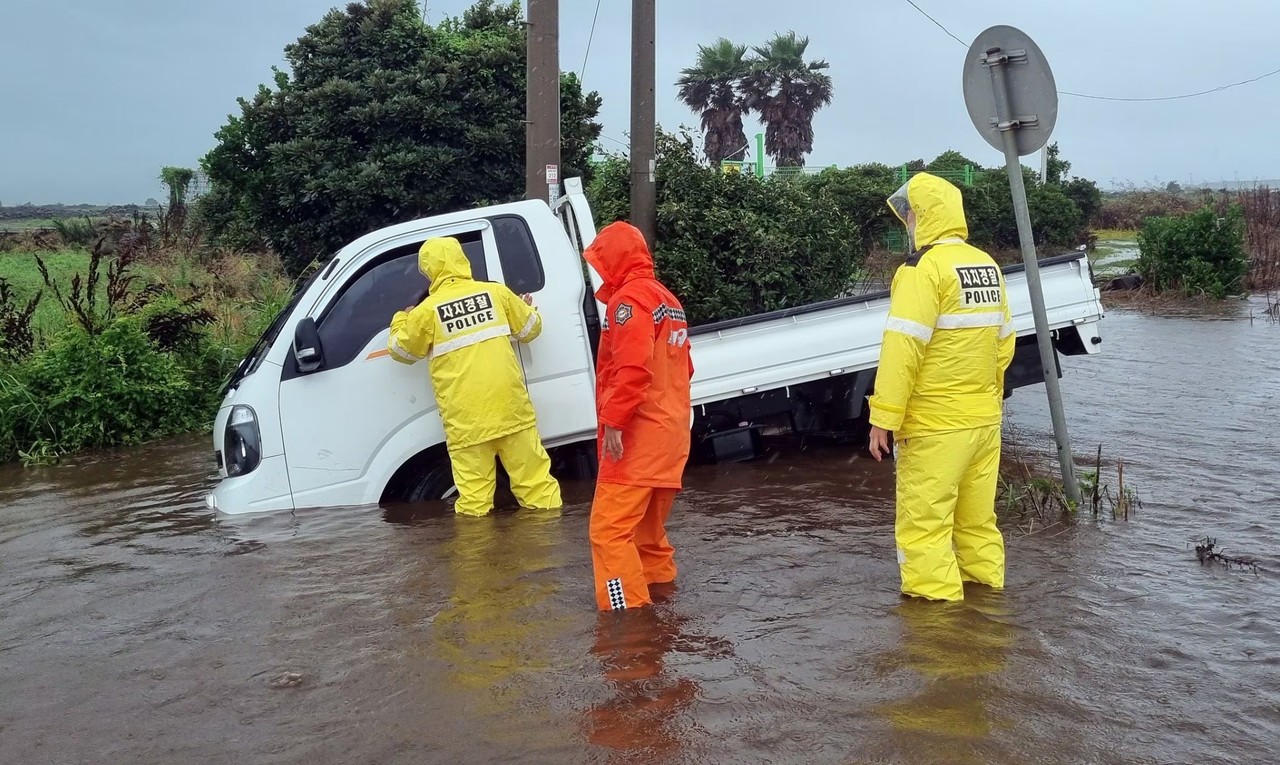 지난 29일 서귀포시 대정읍에서 1톤 트럭이 물이 가득 찬 도로에 빠져 경찰관과 소방관이 안전조치 하고 있다.