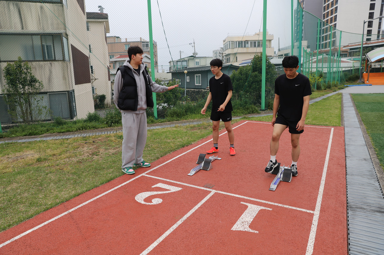 서귀포중학교 박홍범 체육교사가 오동근, 박윤 학생에게 운동 과정에 대해 설명하고 있다.